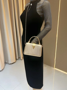 Detailed view of luxury gold evening clutch with snakeskin texture and leaf buckle