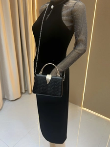 Detail showing luxury black snakeskin texture evening bag with golden bamboo handle