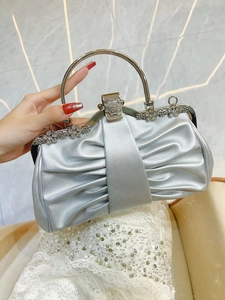 Close-up of silver evening clutch bag featuring rhinestone flowers and metal handle