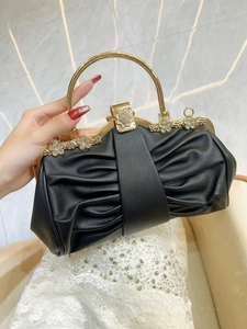 Detail of black pleated evening clutch with gold ring handle and crystal floral embellishment