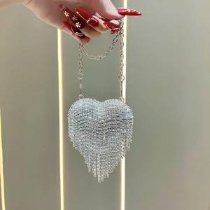 Detail of a sparkling heart-shaped evening bag with silver rhinestones and long tassels