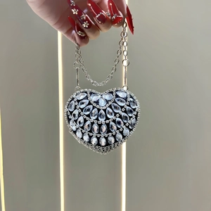 Detail of heart-shaped black evening bag with sparkling rhinestones and silver chain