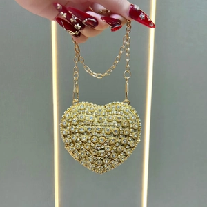 Detailed view of heart-shaped rhinestone evening bag with gold chain and crystals