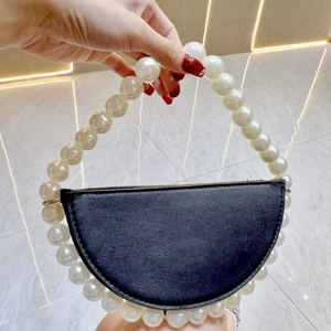 Detail of elegant black semi-circle clutch with large white pearl beaded handle