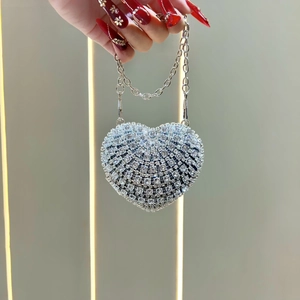 Detail of silver heart-shaped evening bag with sparkling rhinestones and chain strap