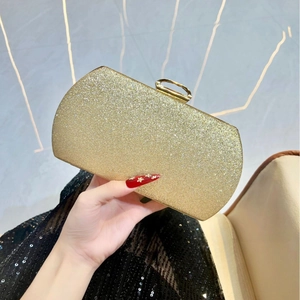Pochette dorée pailletée avec fermoir en métal tenue par une femme en robe de soirée