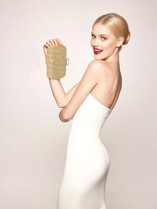 Pochette de soirée dorée avec strass tenue par un mannequin portant une robe blanche chic