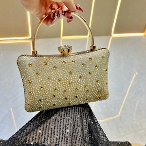 Close-up of champagne gold evening clutch with sparkling rhinestones and metal ring handle
