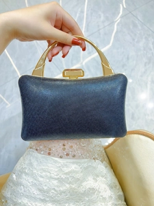 Close-up of elegant black sparkly evening clutch with gold handle held by a woman