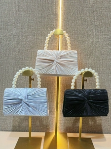 Detail of pleated evening clutches with decorative pearl handles in multiple colors