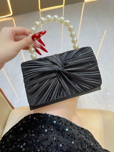 Detail of black pleated evening bag with elegant pearl handle for formal dinner parties