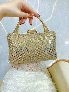 Detailed view of shimmering gold evening clutch bag with crystal rhinestones and metal handle