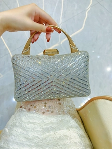 Detailed macro shot of shimmering silver rhinestones and gold handle on the evening clutch