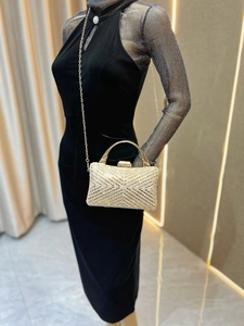 Detail of a gold evening clutch with rhinestones, metal handle and delicate chain strap