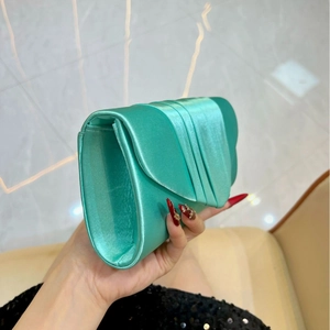 Detail of mint green pleated satin evening clutch bag held in hand for formal occasions