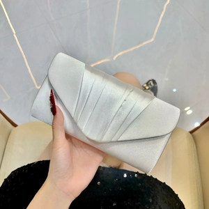 Detail of silver pleated satin evening clutch bag with V-shaped flap held in hand