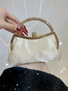 Detailed macro view of beige satin evening clutch with rhinestone handle and crystal clasp