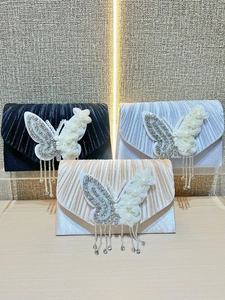 Détail de pochettes de soirée en satin plissé avec papillon en strass et franges brillantes