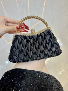 Macro detail of luxury black satin evening bag with rhinestone-encrusted gold handle
