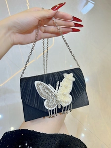 Détail de la pochette de soirée noire avec tissu plissé, papillon en strass et fleurs de perles