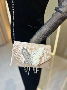 Détail de la pochette champagne avec papillon en strass et pompons de perles