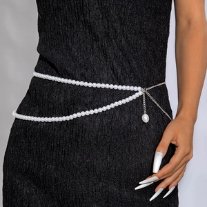 Détail d'une chaîne de taille en perles blanches avec extension sur une robe noire