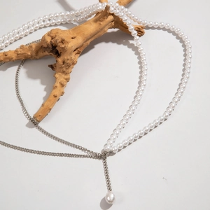 Détail d'une chaîne de corps multicouche avec perles et argent drapée sur un bois naturel