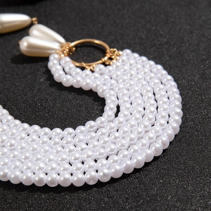 Gros plan de perles blanches multicouches et anneaux dorés avec pendentif goutte