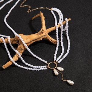 Détail d'une chaîne de corps multicouche en perles avec anneau doré et pendentifs