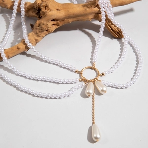 Détail d'une chaîne de corps multicouche en perles avec anneau doré et pendentifs