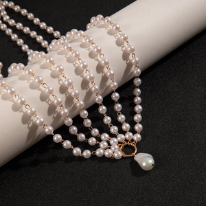 Détail d'une chaîne de taille multicouche en perles avec pendentif baroque doré