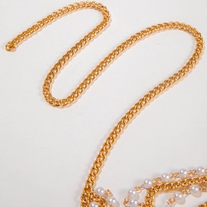 Détail d'une chaîne en métal doré multicouche avec des perles blanches pour la taille ou le corps