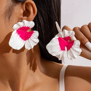 Vibrant orchid-shaped statement earrings in white and magenta matte finish on model