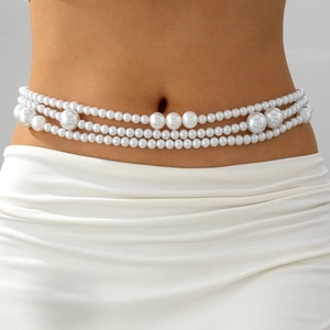Vue détaillée d'une élégante chaîne de taille multicouche en perles sur une robe blanche