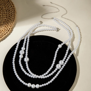 Détail de la chaîne de corps en perles multicouches avec fermoir argenté sur velours noir