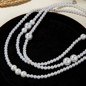 Vue détaillée d'une chaîne de corps multicouche en perles blanches sur velours noir