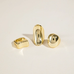 Set di tre anelli dorati lucidi con forme geometriche ovali e irregolari asimmetriche
