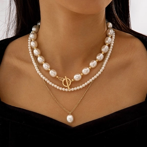 Collier multicouche en perles avec fermoir OT et pendentif doré porté par modèle