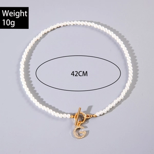 Détail du collier de perles avec fermoir OT doré, pendentif G et spécification de 42 cm