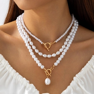 Détail d'un collier de perles multicouche avec fermoirs OT dorés et perle baroque