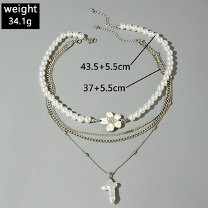 Détail du collier de perles multicouche avec chaînes argentées et pendentif croix