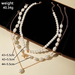 Détail d'un collier de perles à trois rangs avec fermoir OT et pendentif coeur sur velours