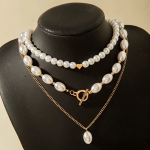 Détail d'un collier multicouche en perles avec fermoir OT doré et pendentif en cœur