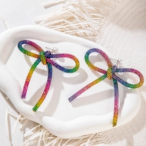Détail de boucles d'oreilles nœud avec strass colorés et perles blanches sur céramique