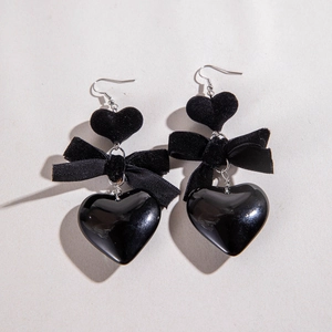 Detail of elegant black velvet bow earrings featuring multi-layered heart resin pendants
