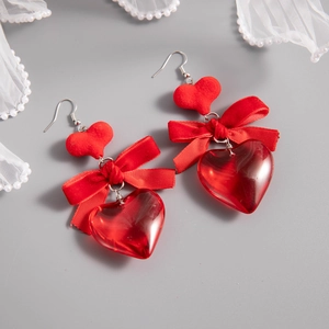 Close-up of red heart earrings with velvet studs, satin bows and acrylic drops