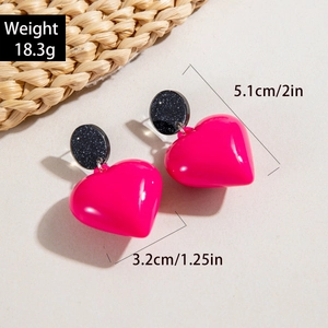 Detail shot of acrylic heart earrings with pink glossy finish and black glitter studs