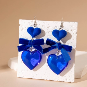 Close-up of blue velvet bow and acrylic heart drop earrings on display card