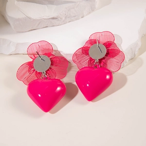 Detailed view of red mesh bow earrings with glossy pink heart drops on a stone stand