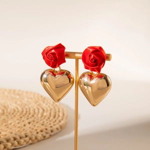 Detailed shot of red fabric rose and gold heart drop earrings on a metal display stand